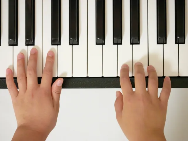 ピアノの鍵盤を指で指し、音階や絶対音感をイメージする子ども